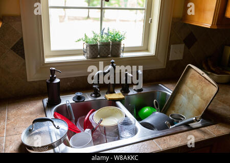 Stack of dirty dishes piled into the kitchen sink Stock Photo