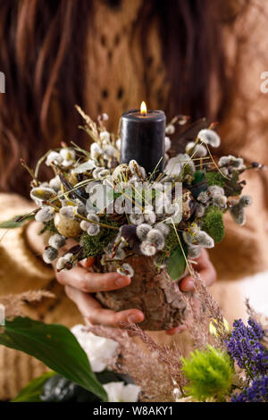 Dried flowers and willow branches in the hands of a girl. decorations, candles, dry willow branches and a female hand on the background. The concept o Stock Photo