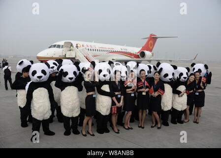 Chinese employees dressed in panda costumes and air hostesses pose in front of a COMAC ARJ21 regional jet of Sichuan Airlines at the Chengdu Shuangliu Stock Photo