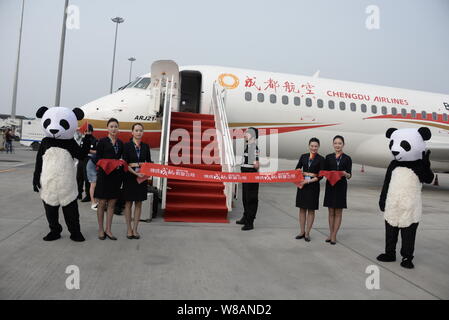 Chinese employees dressed in panda costumes and air hostesses pose in front of a COMAC ARJ21 regional jet of Sichuan Airlines at the Chengdu Shuangliu Stock Photo