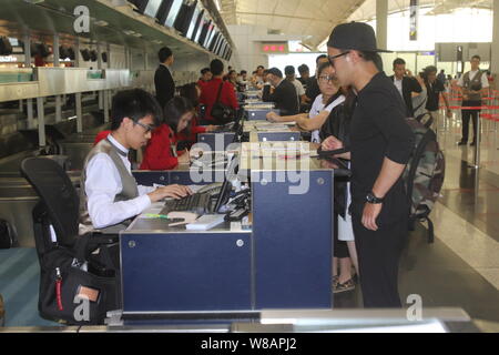 Hong Kong actor Hawick Lau, front right, accompanies his Chinese actress wife Yang Mi, unseen, to get her boarding pass before departure at the Hong K Stock Photo