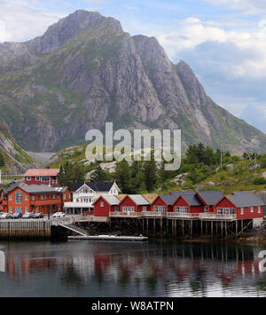 Traditional red colorful Norwegian fishing houses with mountains on the background, Lofoten Islands in northern Norway Stock Photo