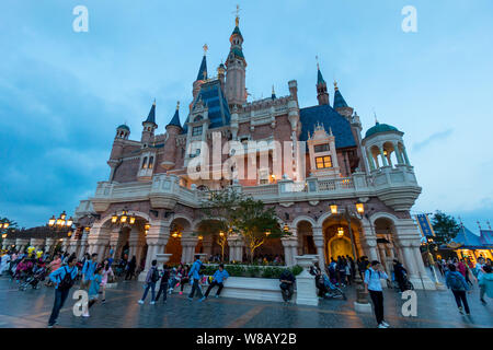 Tourists visit the illuminated Disney Castle in the Shanghai Disneyland during the trial operation at the Shanghai Disney Resort in Pudong, Shanghai, Stock Photo