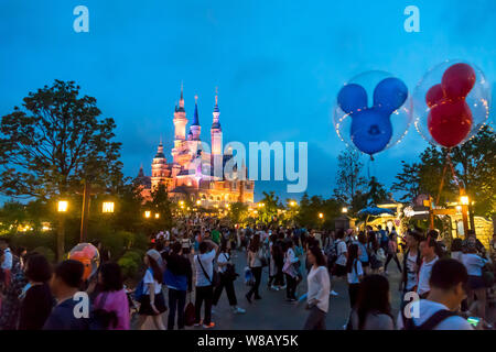 Tourists visit the illuminated Disney Castle in the Shanghai Disneyland during the trial operation at the Shanghai Disney Resort in Pudong, Shanghai, Stock Photo