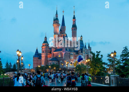 Tourists visit the illuminated Disney Castle in the Shanghai Disneyland during the trial operation at the Shanghai Disney Resort in Pudong, Shanghai, Stock Photo