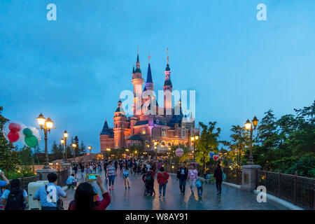 Tourists visit the illuminated Disney Castle in the Shanghai Disneyland during the trial operation at the Shanghai Disney Resort in Pudong, Shanghai, Stock Photo