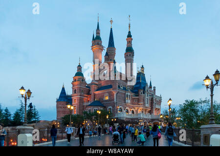 Tourists visit the illuminated Disney Castle in the Shanghai Disneyland during the trial operation at the Shanghai Disney Resort in Pudong, Shanghai, Stock Photo