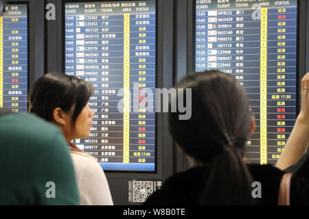--FILE--Passengers look at an electronic display showing that most flights were delayed or cancelled due to thunder storms at the Shanghai Hongqiao In Stock Photo