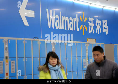 --FILE--Customers walk in a Walmart supermarket in Shanghai, China, 18 January 2016.   At the store in Shanghai, signs promote 'everyday low prices,' Stock Photo