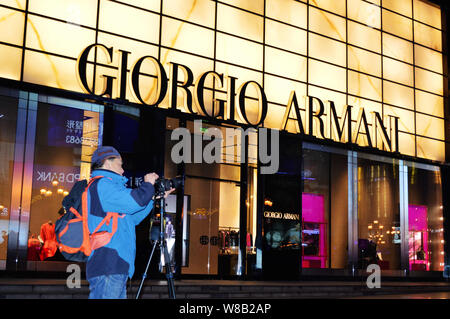 --FILE--A photographer stands in front of a Giorgio Armani store in Chongqing, China, 14 February 2016.   Italian fashion house Giorgio Armani experie Stock Photo