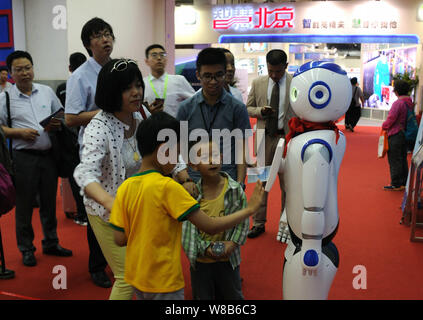 Visitors interact with a robot on display during the 19th China Beijing International High-tech Expo (CHITEC) in Beijing, China, 19 May 2016.   The 19 Stock Photo