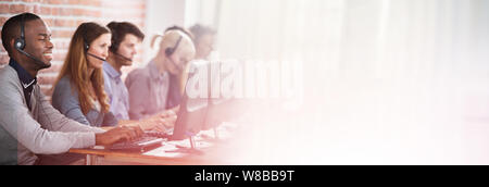 Young Customer Service Executives Using Earphones Working In Call Center Stock Photo