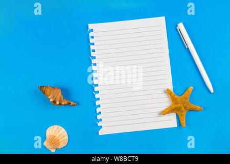 Page ripped off from the notebook, seashells and starfish on blue background. Vacation, travel concept Stock Photo