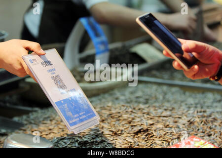 --FILE--A customer uses his smartphone to scan a QR code to pay for snacks he bought through Chinese online payment service Alipay of Alibaba's Ant Fi Stock Photo