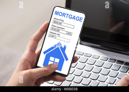 Close-up Of Woman's Hand Filling Mortgage Application Form On Mobilephone Stock Photo