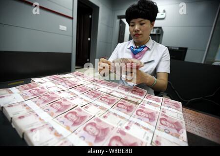 --FILE--A Chinese clerk counts RMB (renminbi) yuan banknotes at a branch of ICBC (Industrial and Commercial Bank of China) in Huaibei city, east China Stock Photo