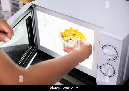 Close-up Of A Person Heating Food In Microwave Oven Stock Photo