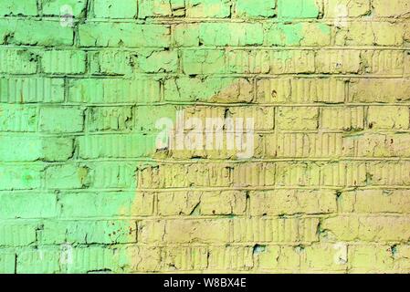 Old painted brick wall brown and green colors close up. Abstract background Stock Photo