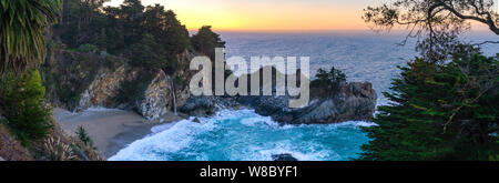 Panorama view of the beautiful waterfall at McWay Falls pouring on to the sandy beach along the Pacific coast in California. Stock Photo
