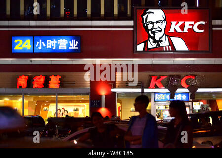 --FILE--Pedestrians walk past a KFC fastfood restaurant of Yum Brands in Qiqihar city, northeast China's Heilongjiang province, 27 August 2014.   Shar Stock Photo