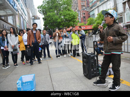 Nine-year-old boy Ye Jianjun sings a song to beg for money on a street in Changsha city, central China's Hunan province, 6 April 2016.   A young Chine Stock Photo