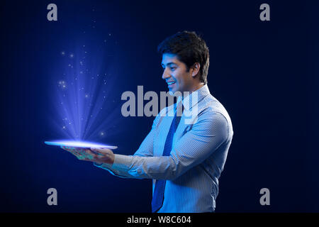 Businessman looking at lights coming from digital tablet Stock Photo