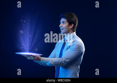 Businessman looking at lights coming from digital tablet Stock Photo