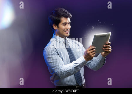 Businessman looking at lights coming from digital tablet Stock Photo