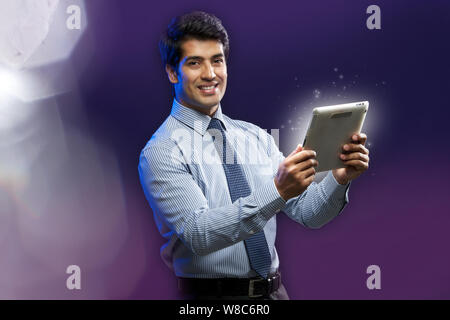 Businessman holding a digital tablet and lights streaming from it Stock Photo