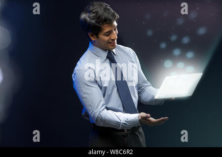 Businessman looking at lights coming from digital tablet Stock Photo