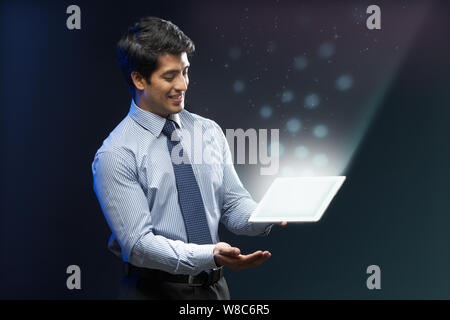 Businessman looking at lights coming from digital tablet Stock Photo