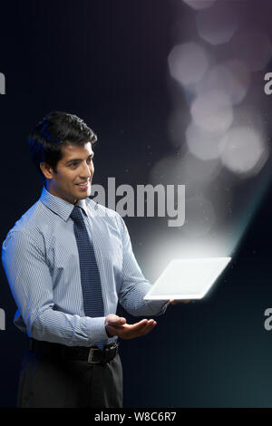 Businessman looking at lights coming from digital tablet Stock Photo