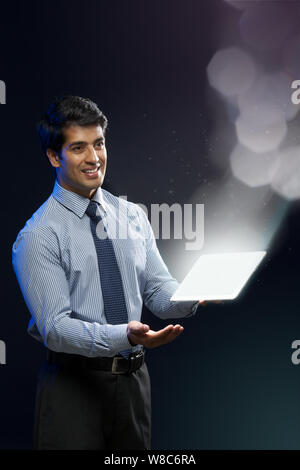 Businessman looking at lights coming from digital tablet Stock Photo