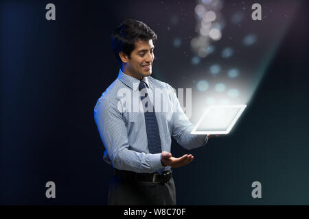 Businessman looking at lights coming from digital tablet Stock Photo