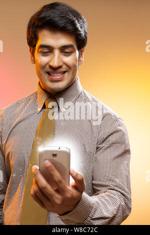 Businessman looking at lights coming from smart phone Stock Photo