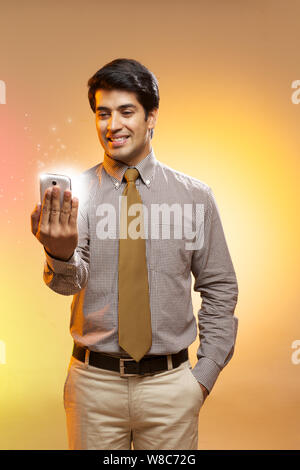 Businessman looking at lights coming from smart phone Stock Photo