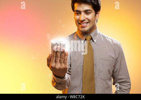 Businessman looking at lights coming from smart phone Stock Photo
