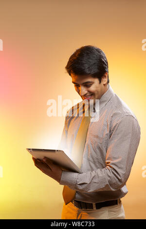 Businessman looking at lights coming from digital tablet Stock Photo
