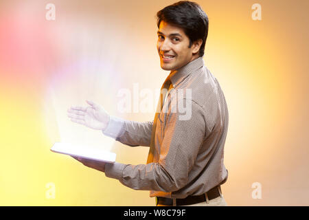 Businessman using a digital tablet and lights streaming from it Stock Photo