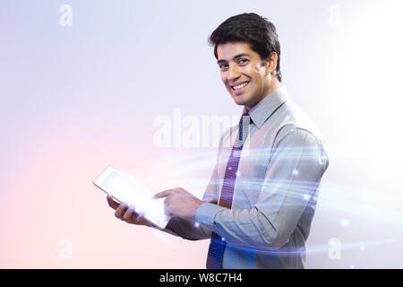 Businessman using a digital tablet and lights streaming from it Stock Photo