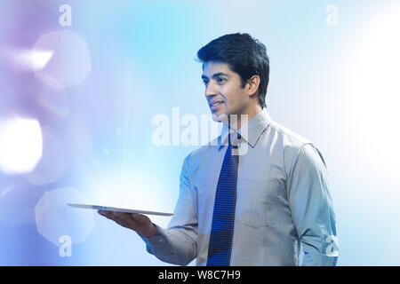 Businessman looking at lights coming from digital tablet Stock Photo