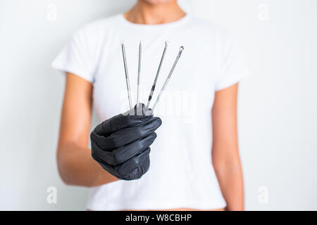 Tools for removing acne. Tools of the cosmetologist for problem skin in woman's hand in black glove Stock Photo