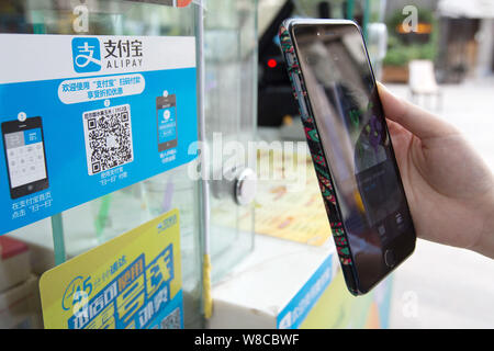 --FILE--A customer uses her smartphone to scan a QR code to pay by Alipay at a booth in Nanjing city, east China's Jiangsu province, 28 August 2015. Stock Photo