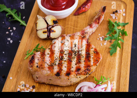 Raw pork steak with herbs on dark background. Raw juicy steak on bone Stock Photo