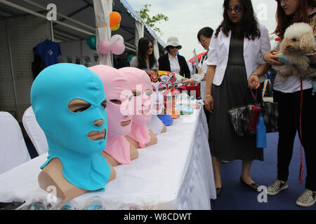Visitors look at facekini masks by Chinese facekini designer Zhang Shifan on display at her stand during the 13th China International Marine Fair and Stock Photo