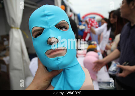 Visitors look at facekini masks by Chinese facekini designer Zhang Shifan on display at her stand during the 13th China International Marine Fair and Stock Photo