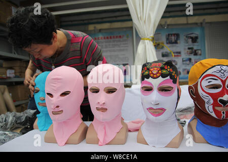 Chinese facekini designer Zhang Shifan puts Peking Opera and other facekini masks on display at her stand during the 13th China International Marine F Stock Photo