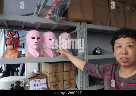 Chinese facekini designer Zhang Shifan poses next to Peking Opera and other facekini masks on display at her stand during the 13th China International Stock Photo