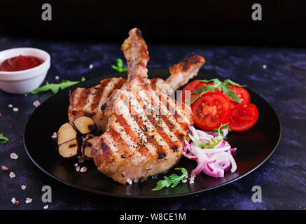 Raw pork steak with herbs on dark background. Raw juicy steak on bone Stock Photo