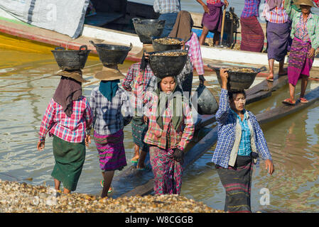 BAGAN, MYANMAR - DECEMBER 23, 2016: Burmese women unload a barge with river pebbles Stock Photo